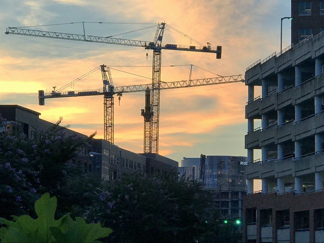 Tower cranes over a construction site at sunset