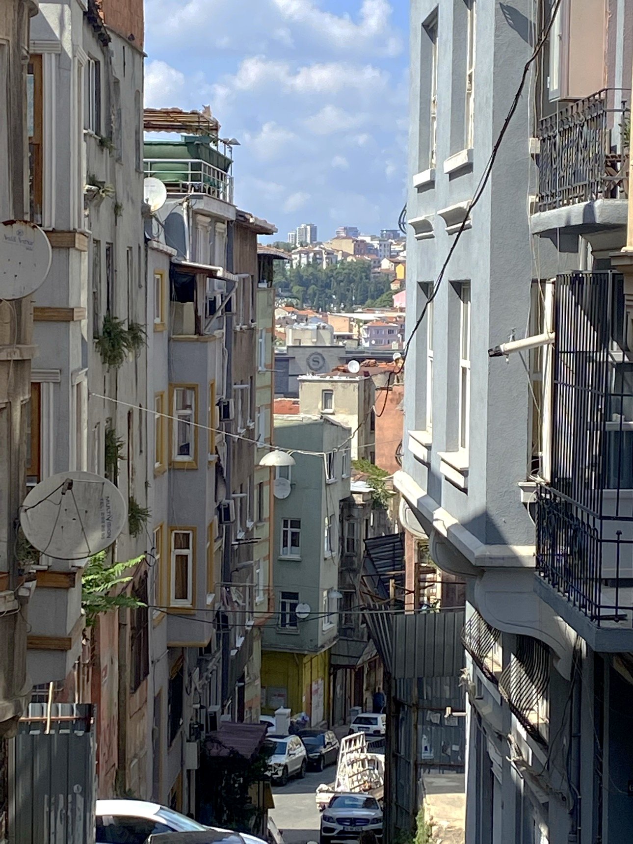 A steep street dropping between apartment blocks toward the city below
