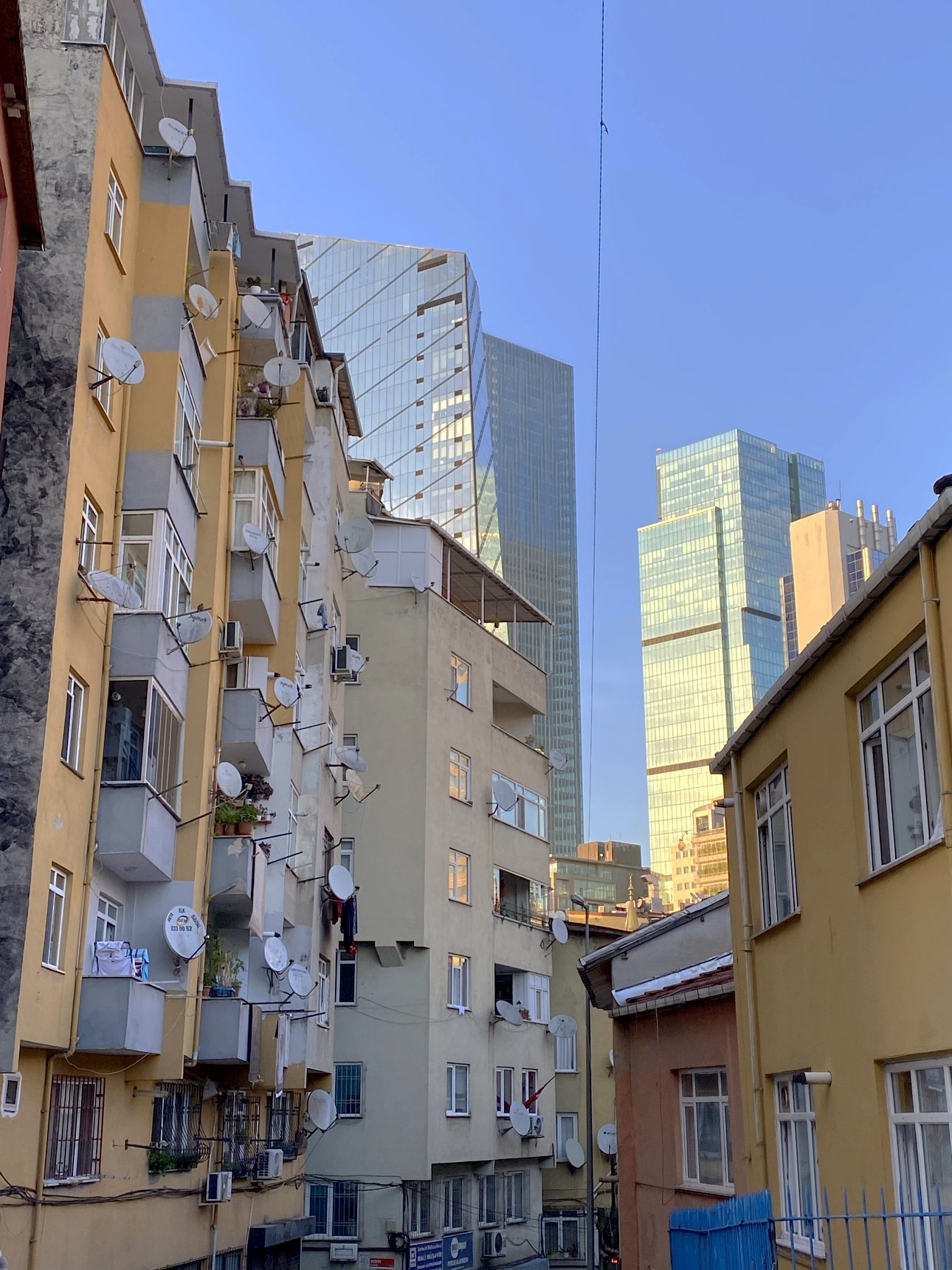 Old apartment blocks with satellite dishes, glass towers rising behind